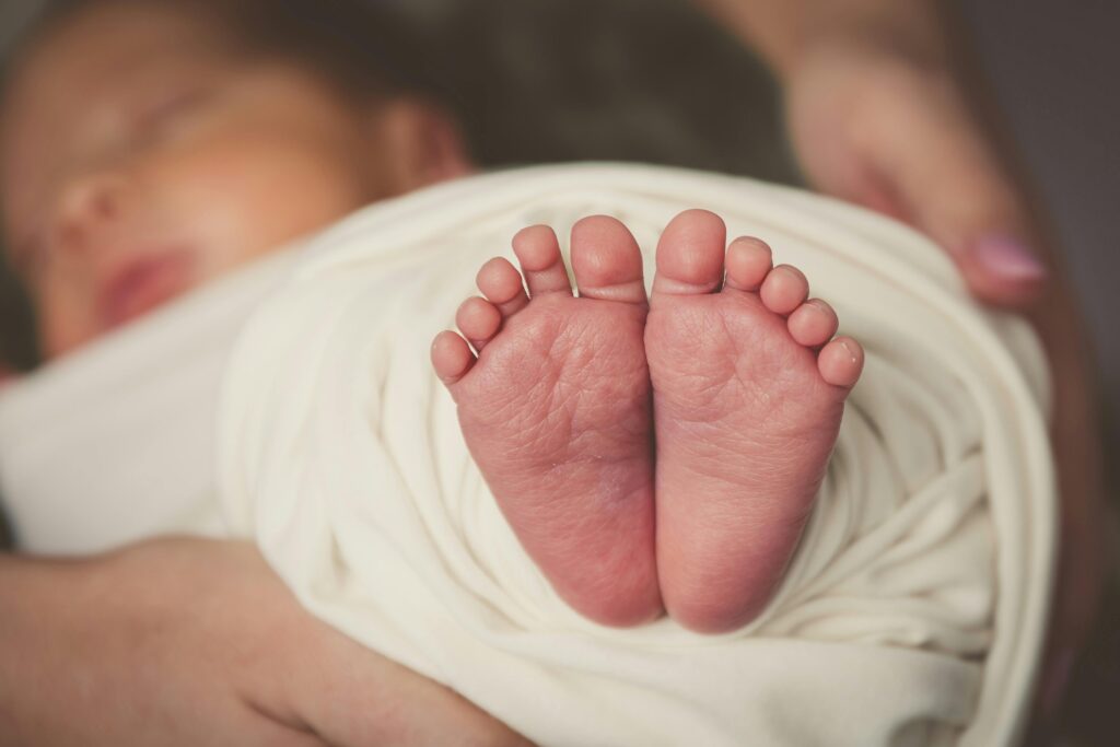 Adorable newborn baby feet wrapped in soft white blanket, capturing innocence and delicacy.